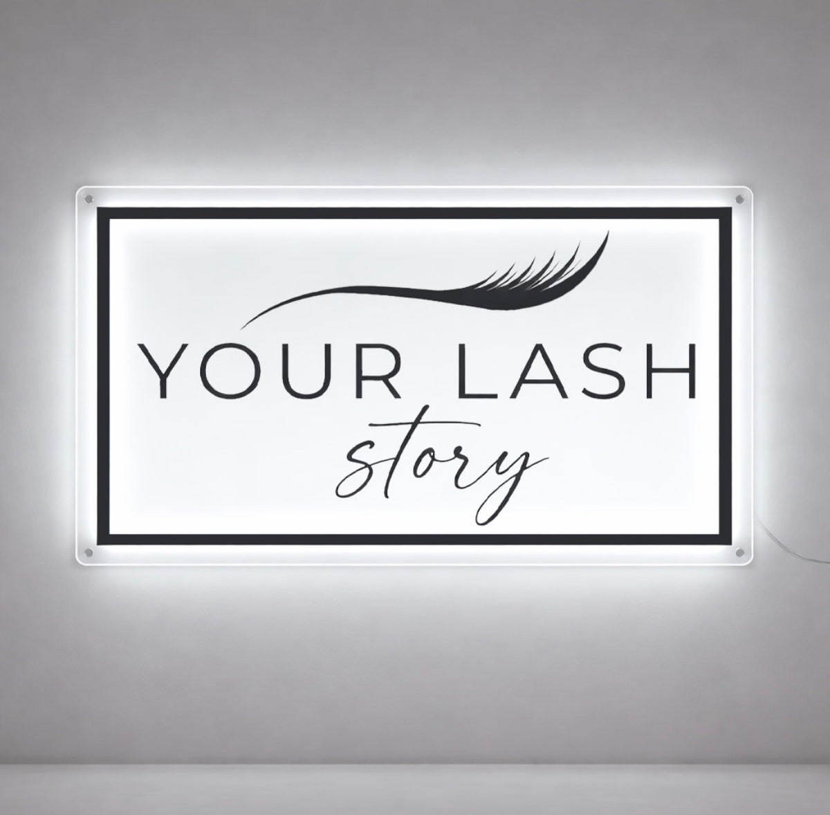 Your Lash Story rectangular halo backlit clear acrylic sign with lash illustration and script tagline, lash salon interior with bright white LED glow.