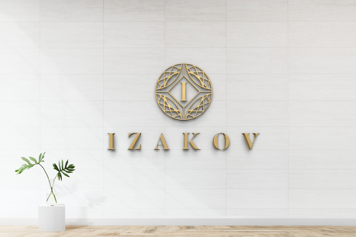 Gold circular geometric logo with letter I and IZAKOV text on white tiled wall, glass vase with monstera leaves.