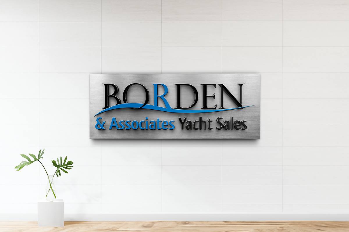 A brushed metal sign reading 'BORDEN & Associates Yacht Sales' with a blue wave logo on a white tiled wall.