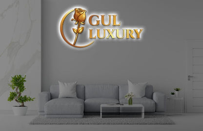 Modern gray living room with light-gray sofa, glass coffee table, potted plants and illuminated gold GUL LUXURY logo.