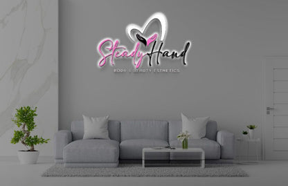 Gray living room with sofa, plants and coffee table beneath pink-black 'Steady Hand' logo, text Body & Beauty Esthetics.