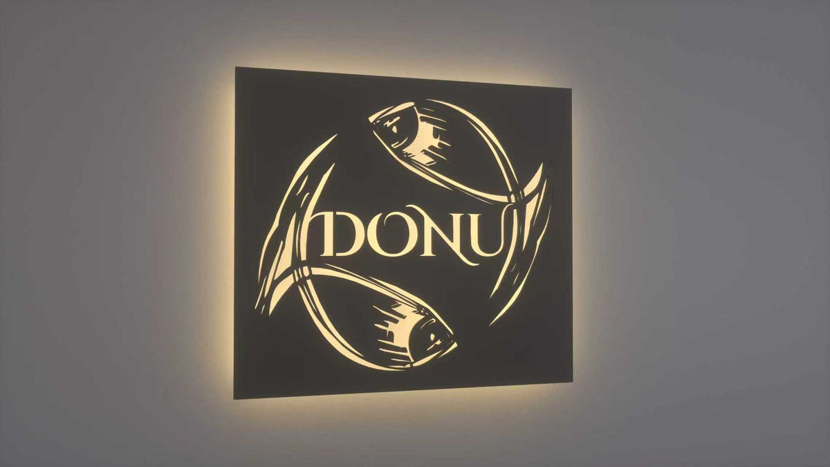 Backlit black square wall sign with glowing cutout of three stylized fish forming a circle around 'DONU' logo.