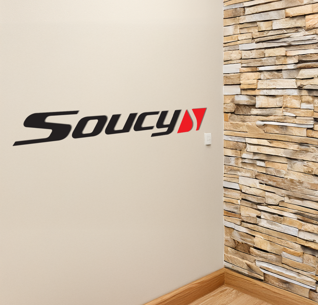 A black and red Soucy logo decal on a beige interior wall next to a stacked stone accent wall and light switch.