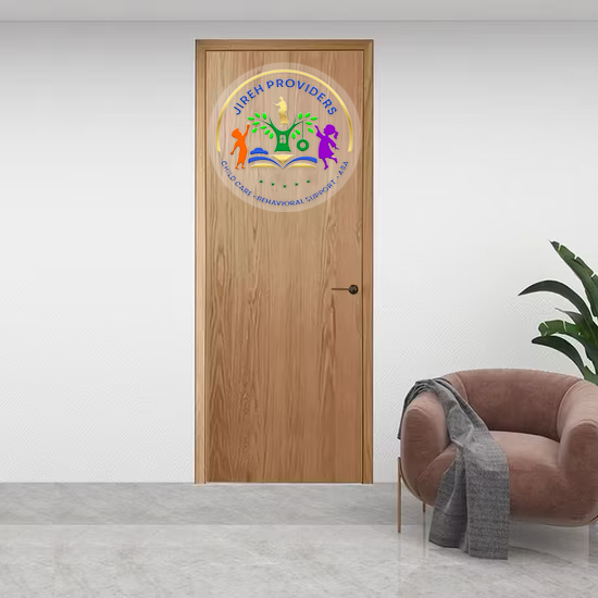 A wooden door with a circular 'Jireh Providers' logo, beside a pink armchair, gray throw and green plant.
