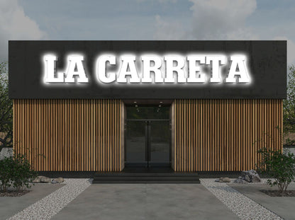 Modern storefront with glowing white 'LA CARRETA' sign on dark facade above vertical wood slats, glass double door.