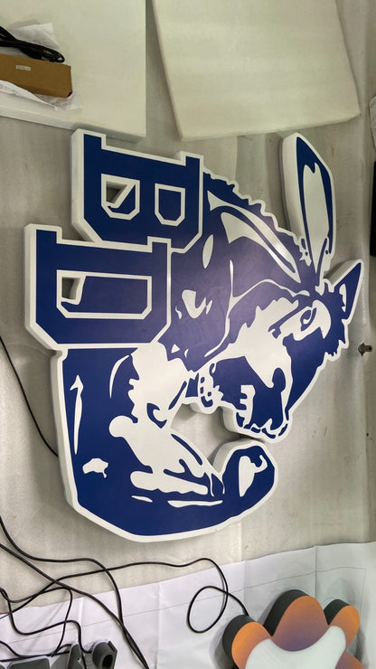 Blue and white cutout mascot sign of a snarling donkey with block letters on foam backing, cords nearby.