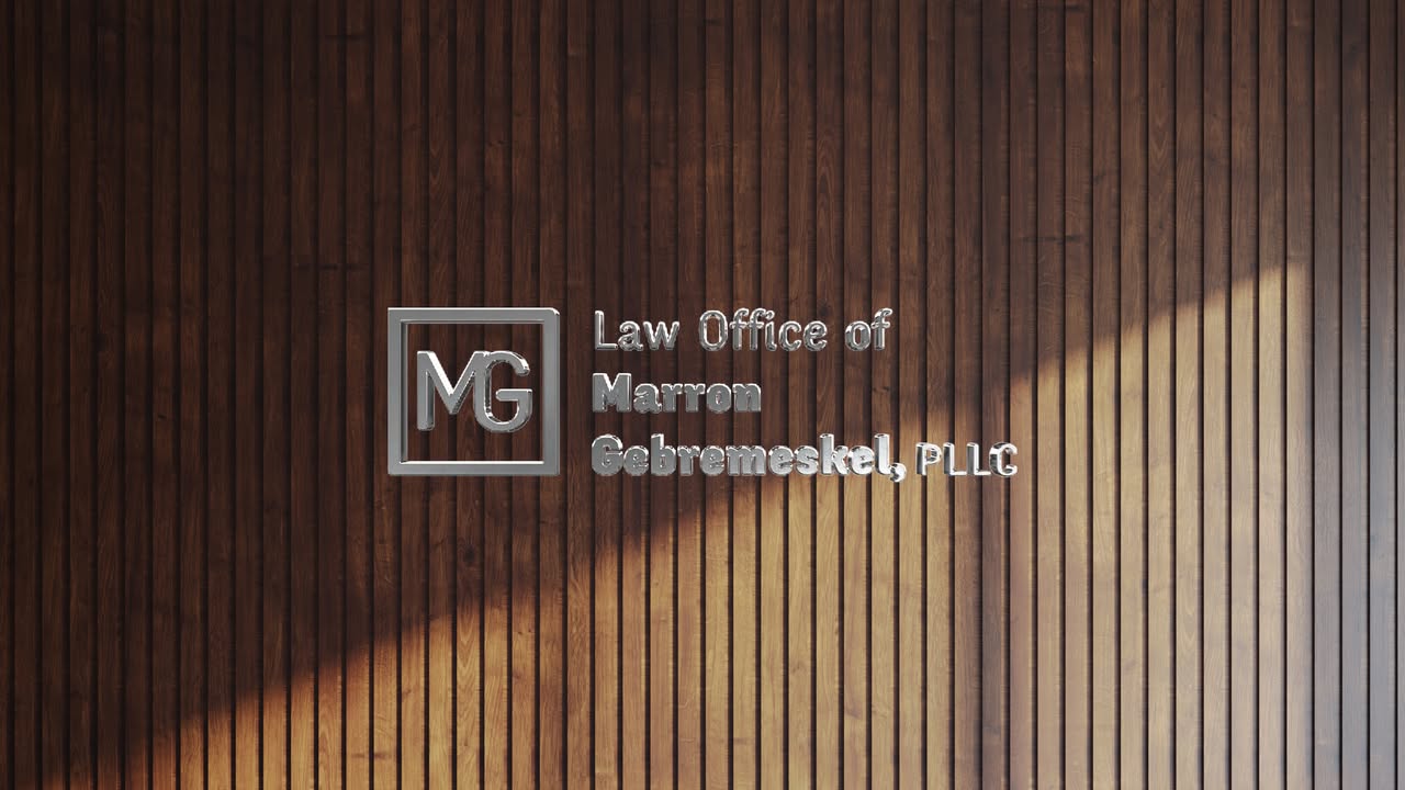 Silver metallic 'MG' logo and 'Law Office of Marron Gebremeskel, PLLG' sign on vertical dark brown wood panels.
