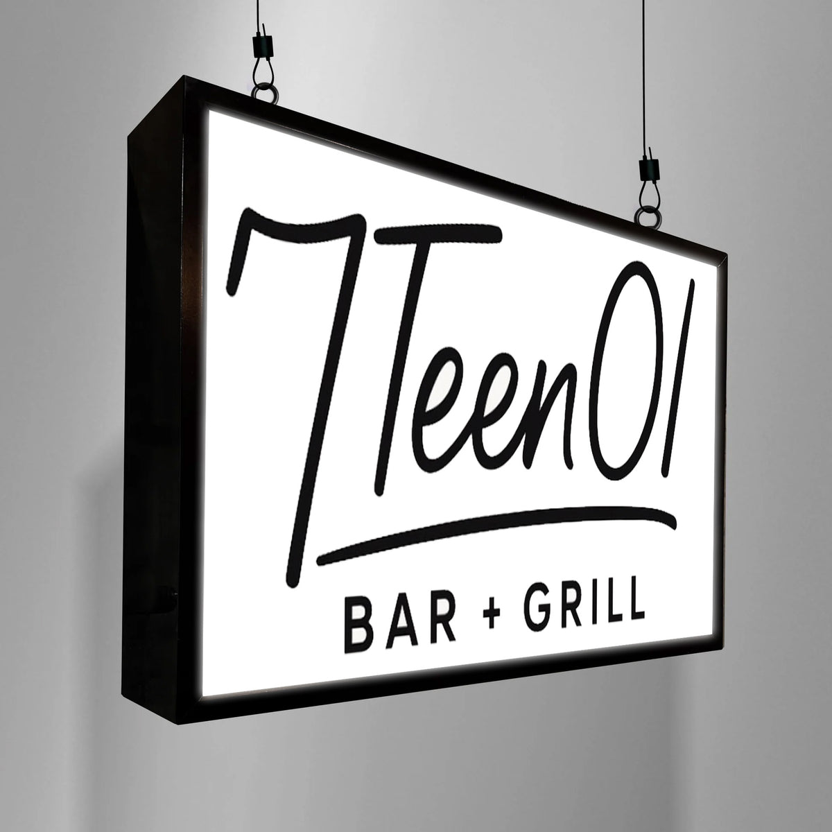 Illuminated hanging black-framed sign with white face reading 'TleenO' and 'BAR + GRILL', suspended by cables.