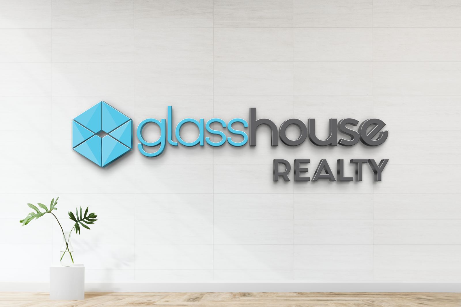Glasshouse Realty 3D dimensional logo sign with blue hex house icon and gray wordmark, nonlit real estate office mockup on tile wall.
