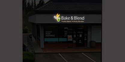 Bake & Blend lit storefront sign with whisk, wheat and green cup logo and tagline 'Freshly Baked. Perfectly Blended.'