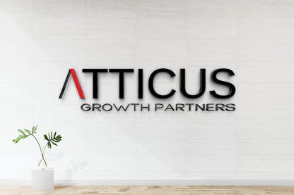 Atticus Growth Partners black 3D logo with red A mounted on white tiled wall above glass vase plant.