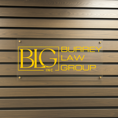A clear glass plaque mounted on a brown horizontal wood wall displays a yellow BLG Inc logo and 'Burrey Law Group' text.