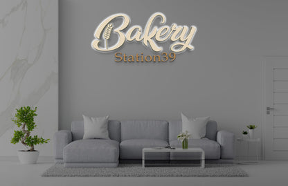 3D backlit custom sign mockup reading Bakery Station39 mounted on gray wall above modern sofa for Volt Signs