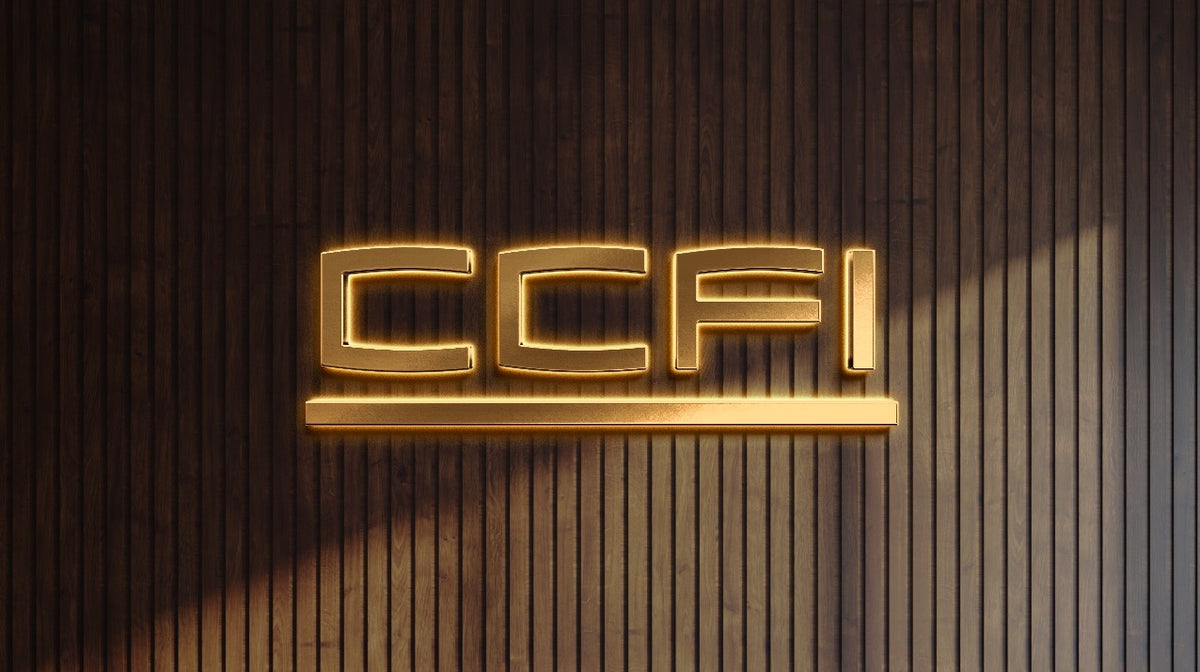 Golden illuminated 'CCFI' backlit sign with glowing underline mounted on dark vertical wood slat wall, warm light.
