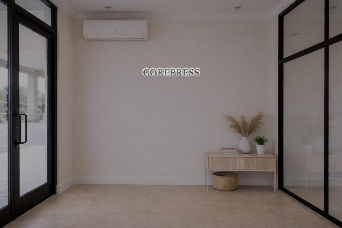 Beige entry wall with 'COREPRESS' sign and white AC, black glass doors, wood console, vase, pampas and basket