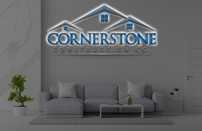 Gray living room with sofa, glass coffee table, potted plants and illuminated blue Cornerstone Construction Co. wall.