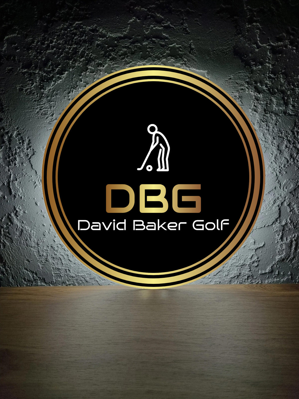 Black circular logo with gold rings, white golfer icon above gold 'DBG' and white 'David Baker Golf' text.