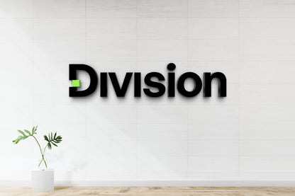 Custom Division 3D black dimensional logo sign with green accent square by Volt Signs, nonlit office lobby signage on tile wall.