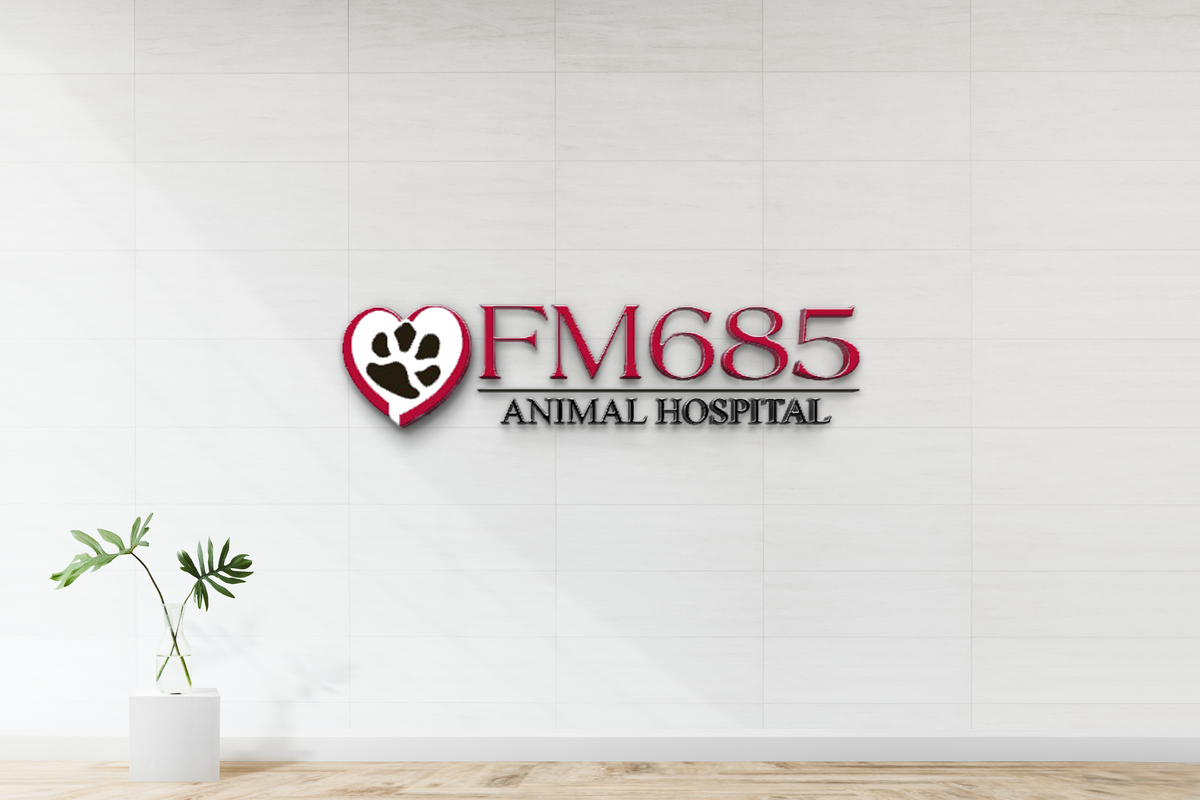 White tiled wall with red FM685 logo and heart paw above ANIMAL HOSPITAL, vase with green leaves on pedestal.