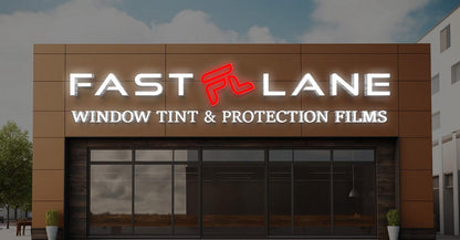 Storefront with illuminated FAST LANE sign and red FL logo above 'WINDOW TINT & PROTECTION FILMS' on brown paneling.