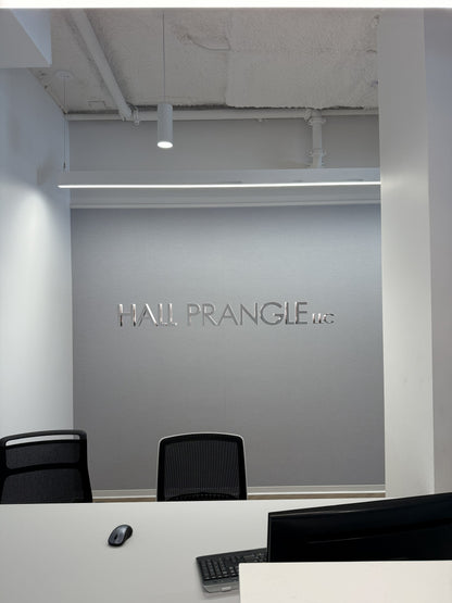 Reception desk with black mesh chairs, white countertop, mouse and keyboard, gray wall with mirrored HALL PRANGLE LLC.