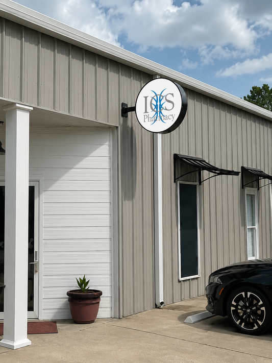 Round illuminated custom double-sided sign mounted on beige metal building exterior for pharmacy business by Volt Signs