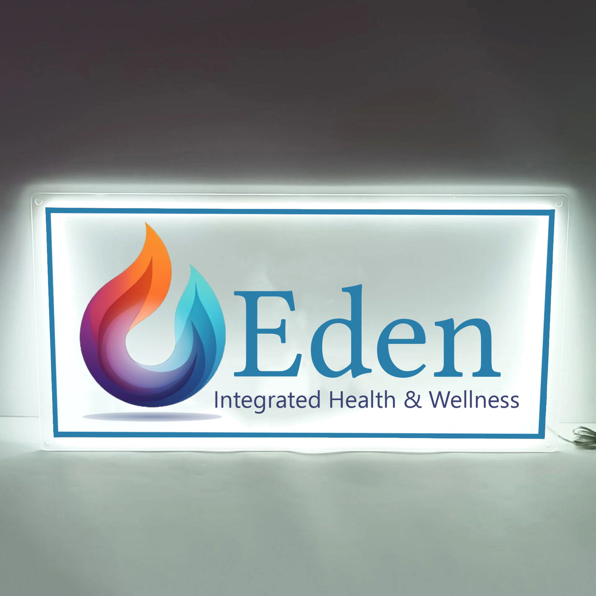 Backlit white sign with blue border multicolored flame droplet logo and large 'Eden' with 'Integrated Health &.