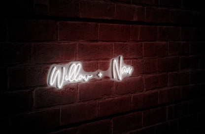 White neon cursive sign reading 'Willow + Naur' glowing on a dark red textured brick wall in shadow.