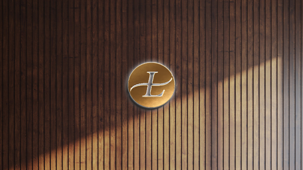 Custom round gold metal L monogram sign with halo LED backlighting, brushed disc with elegant cut letter on dark wood slat wall.