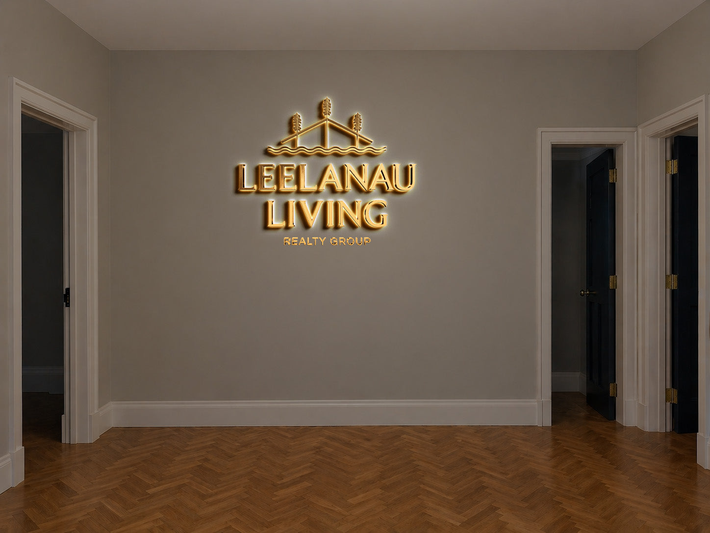 Leelanau Living Realty Group 3D gold halo backlit logo sign with sailboat emblem on luxe office wall with herringbone wood floor.
