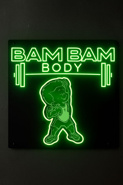 Glowing green neon sign on black wall reading BAM BAM BODY with barbell graphics and a flexing cartoon child mascot.