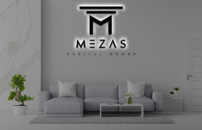 Illuminated MEZAS Capital Group wall logo above modern light-gray sofa, glass coffee table, potted plants.