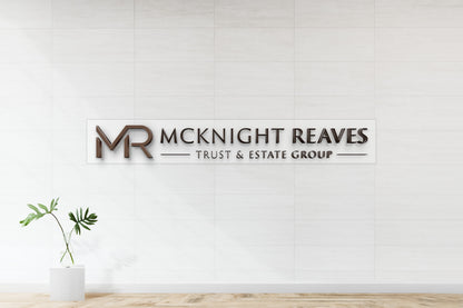 McKnight Reaves Trust & Estate Group 3D bronze letter sign on clear acrylic backplate, nonlit office wall mockup with standoff mounting.