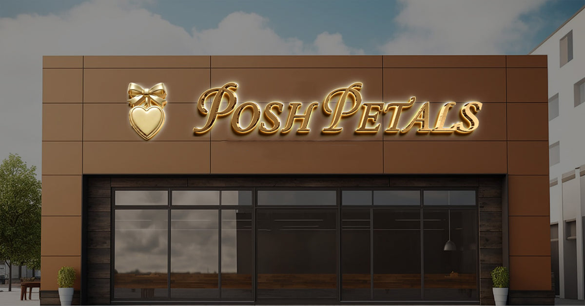 Gold illuminated 'Posh Petals' script and gold heart-with-bow emblem on brown flower shop facade above glass doors.