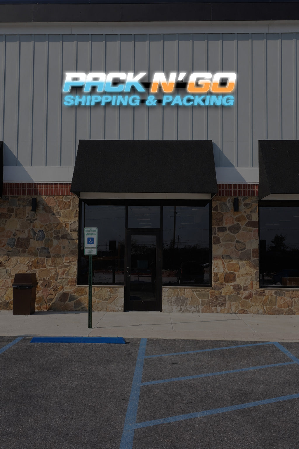 Pack N Go Shipping and Packing real installed storefront sign with face-lit blue orange and white channel letters on raceway above stone facade entrance.