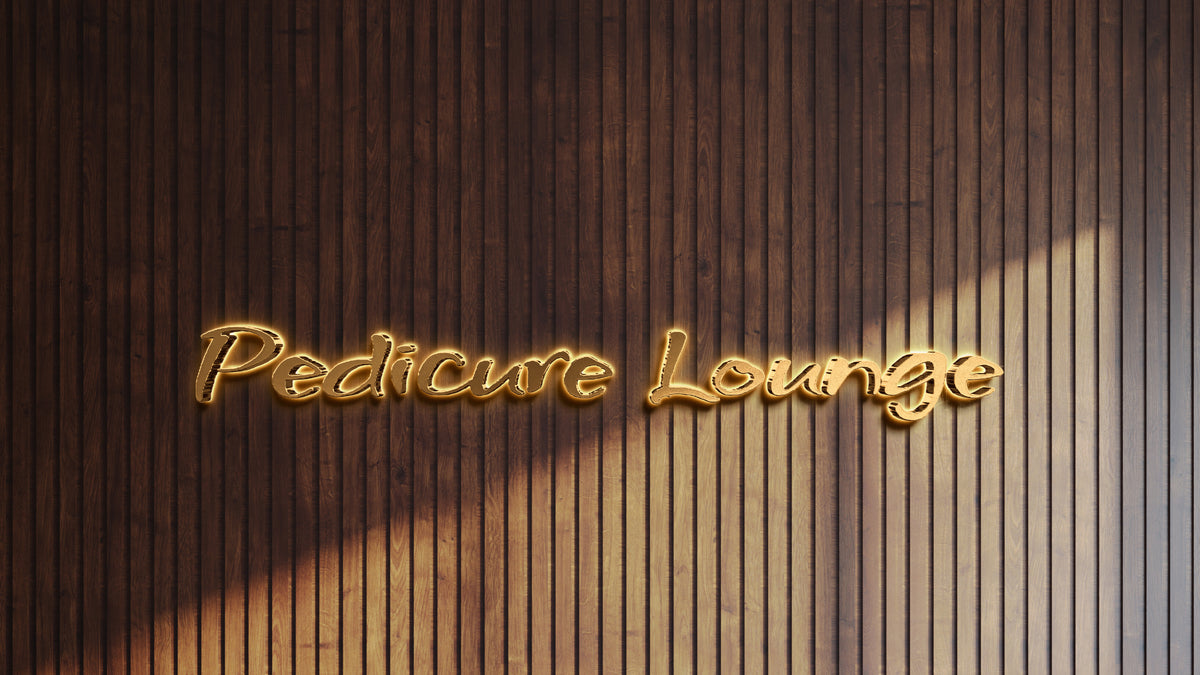 Illuminated gold script sign reading Pedicure Lounge mounted on dark vertical wooden slat wall with soft shadows.