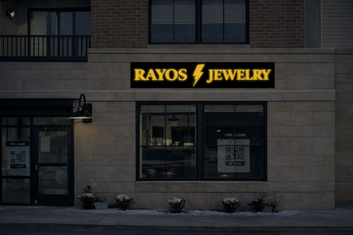 Beige stone storefront with illuminated black sign reading 'RAYOS' lightning bolt 'JEWELRY' in yellow.