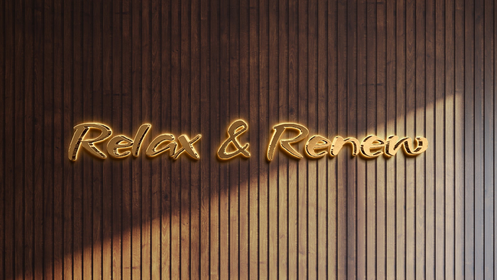 Dark brown vertical wood slat wall with glowing golden script sign reading 'Relax & Renew' centered low.
