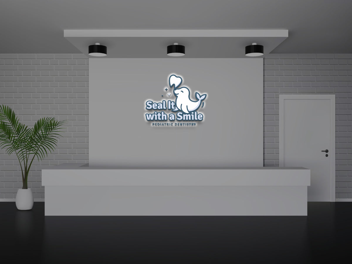 Grey pediatric dentistry reception with backlit 'Seal It with a Smile' blue whale logo, white desk, potted plant, door.