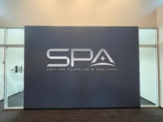 Interior dark gray wall with large white 'SPA' logo featuring a star and wave motif, flanked by glass doors.