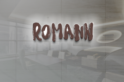 Glossy brown 'ROMANN' sign with white halo mounted on glass over blurred gray office interior with table and chairs.
