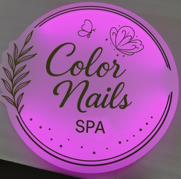 Round glowing pink-purple salon sign reading 'Color Nails SPA' with black script text, butterfly icons and leaf motif.