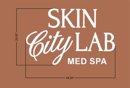 Brown background sign with white text 'SKIN City LAB MED SPA' in mixed fonts and black measurement lines 28.00" 44.00".