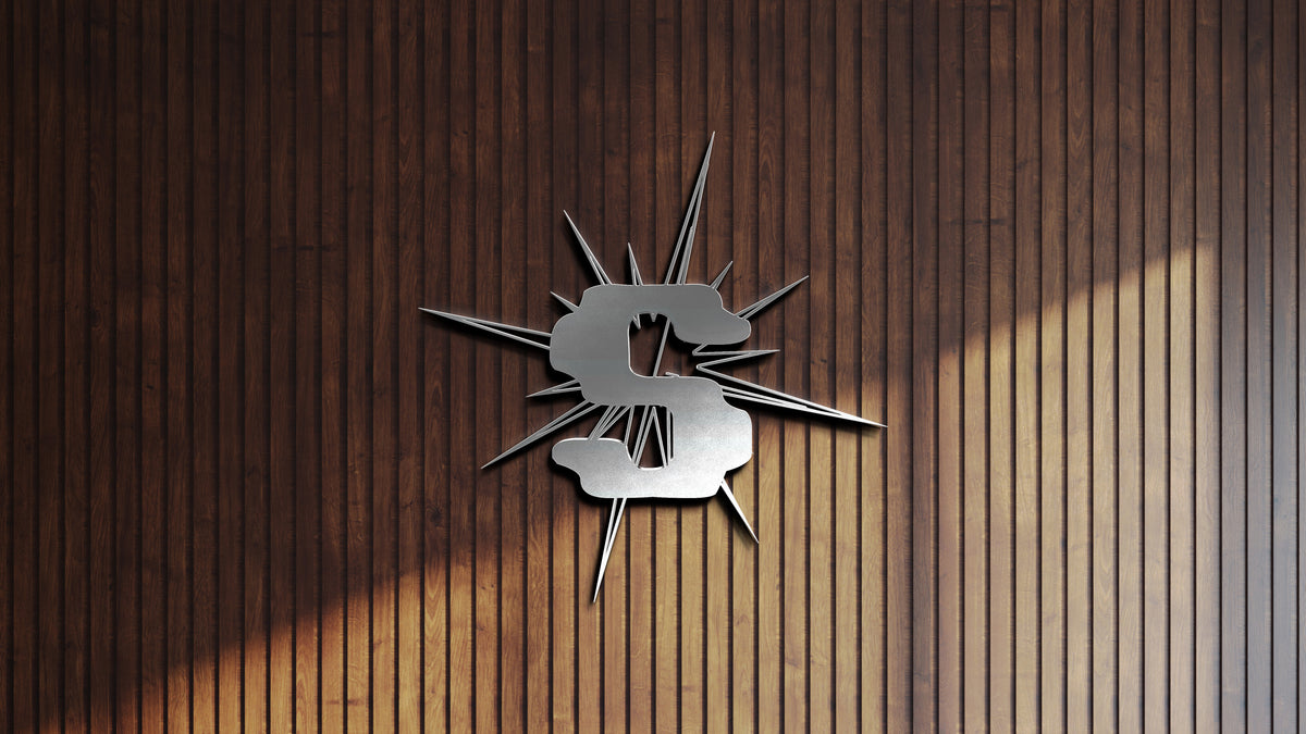 Metallic silver dollar sign slashed with radiating spikes mounted on dark vertical wooden slat wall.