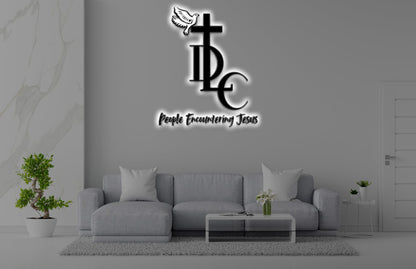 Minimalist living room with gray sofa, coffee table, wall logo of cross and dove saying People Encountering Jesus.