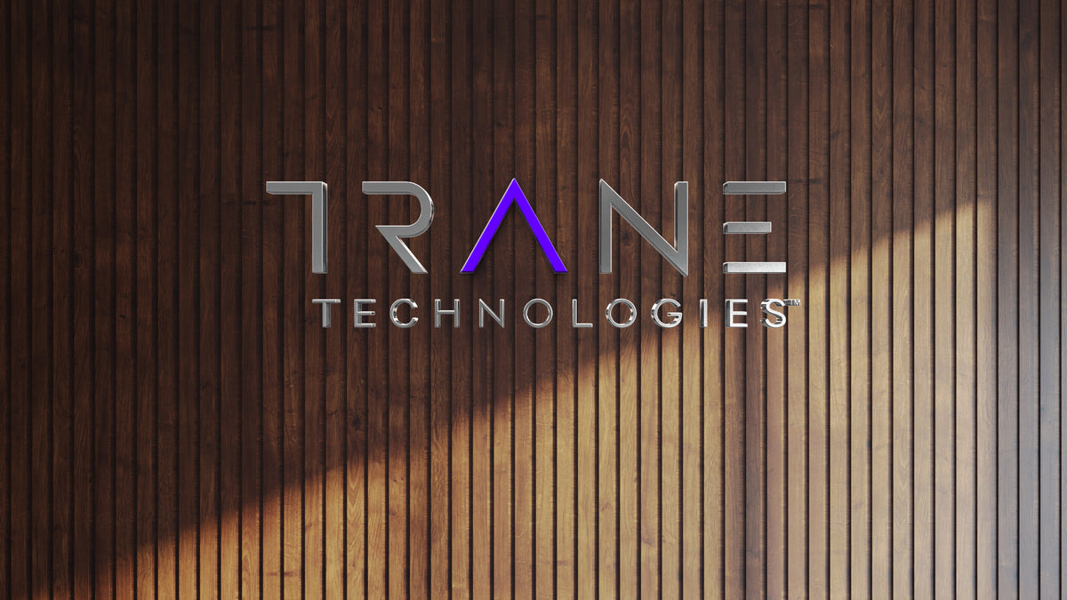 Trane Technologies 3D polished chrome metal logo install with purple triangular A accent on dark wood slat interior wall, HVAC brand.