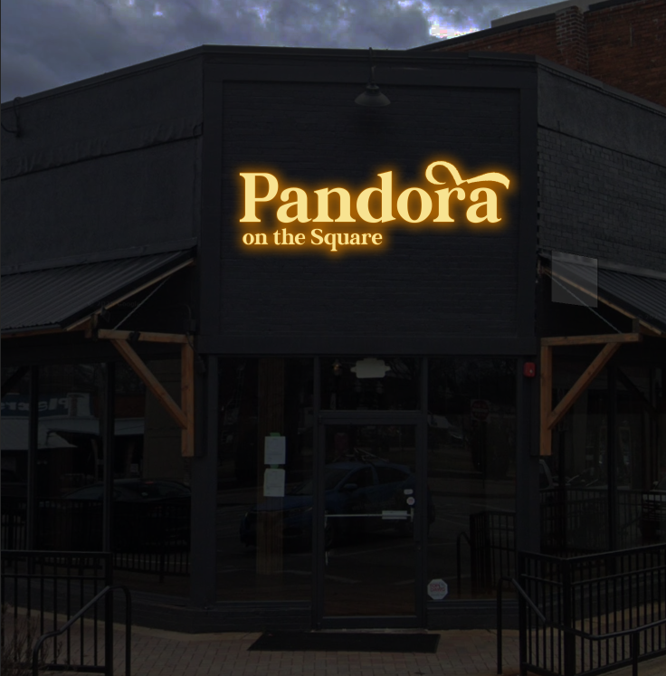 Illuminated golden 'Pandora on the Square' sign on a black storefront with glass doors, wooden awnings.