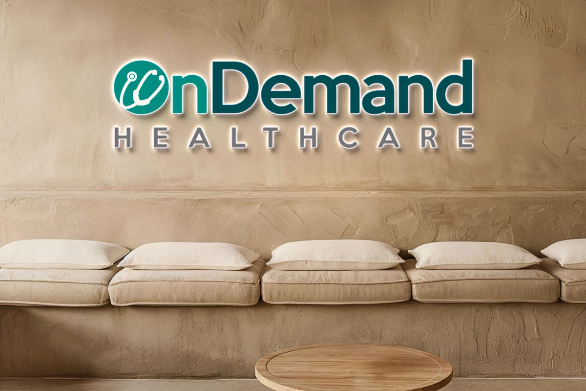 OnDemand Healthcare teal logo with stethoscope icon on beige plaster wall above cushioned bench and round wooden table.