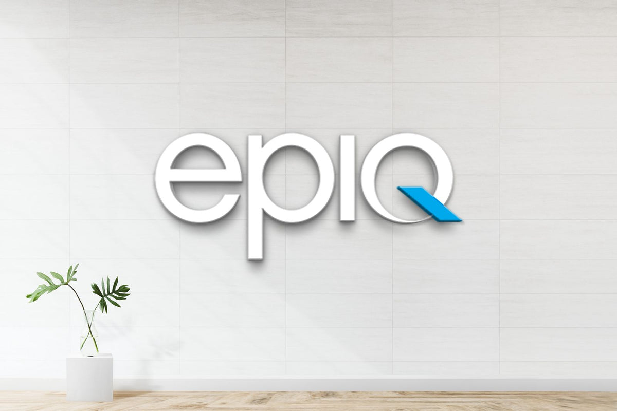 3D white epiq logo with blue ribbon on the q on pale tiled wall above wood floor; glass vase with green leaves.