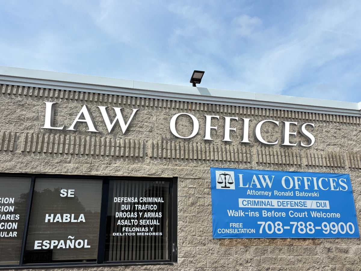 White raised 'LAW OFFICES' on beige brick facade, blue banner phone 708-788-9900, window reads SE HABLA ESPAÑOL.